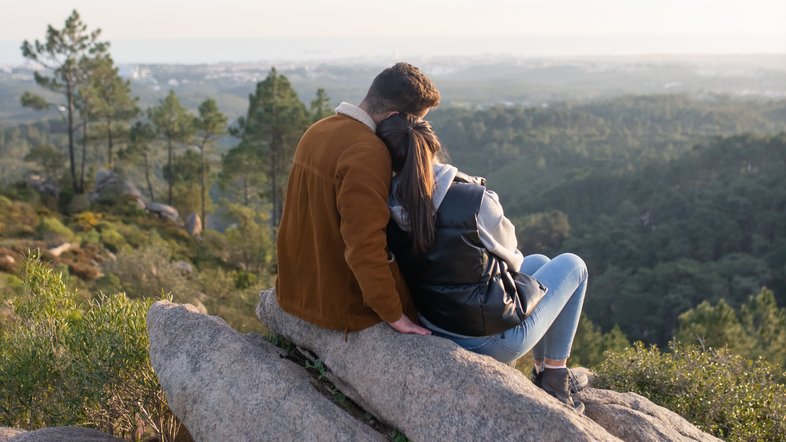 Casal contempla natureza do alto de uma montanha