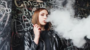 Menina expele fumaça após um trago em cigarro eletrônico (vape)