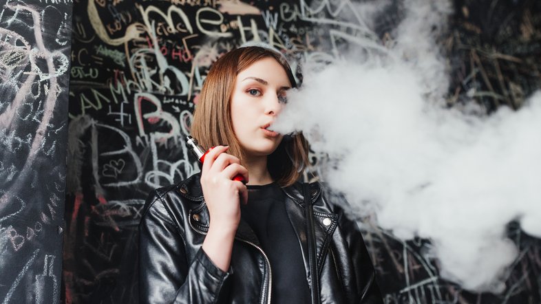 Menina expele fumaça após um trago em cigarro eletrônico (vape)